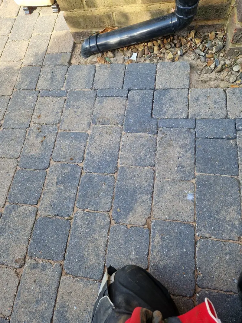 Block paving relaid beside the downpipe after the supply pipe work