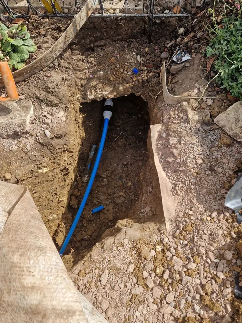 New blue MDPE supply pipe connected in the excavation