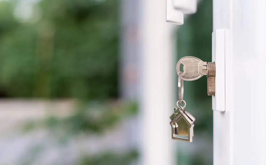 House key with a house-shaped keyring in the lock of a front door